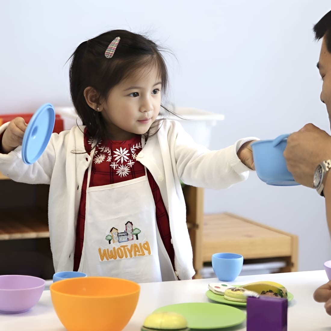 一位幼儿在游戏式疗程中,伸手拿取大人手中的偏好物品。